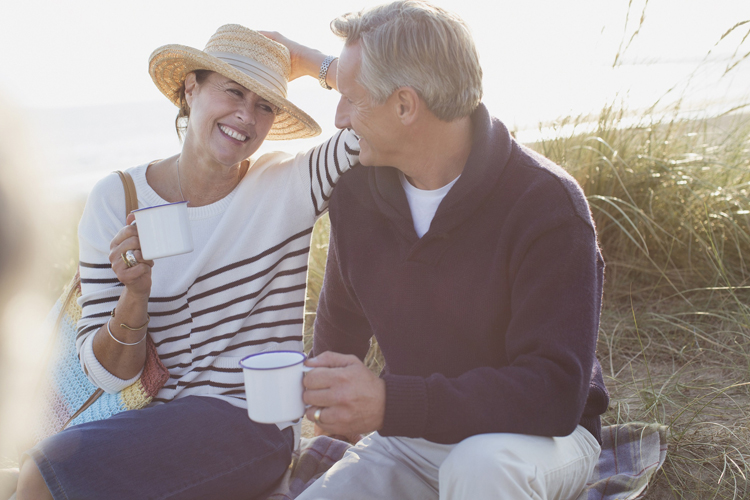 Mann und Frau sitzen auf einer Bank und rrinken Tee
